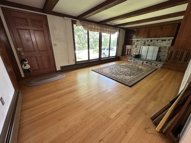 unfurnished living room with a baseboard heating unit, a fireplace, light hardwood / wood-style floors, and beam ceiling