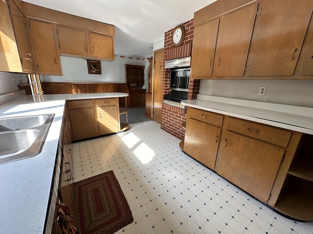 kitchen featuring multiple ovens, wood walls, and sink