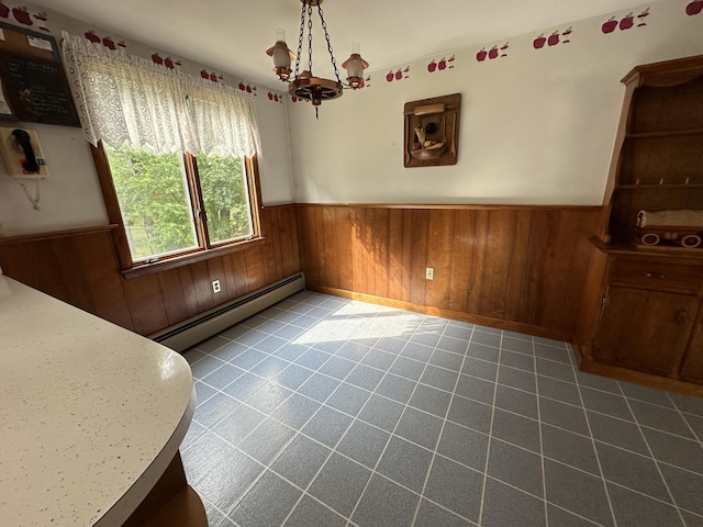 tiled dining room with baseboard heating, wood walls, and a notable chandelier