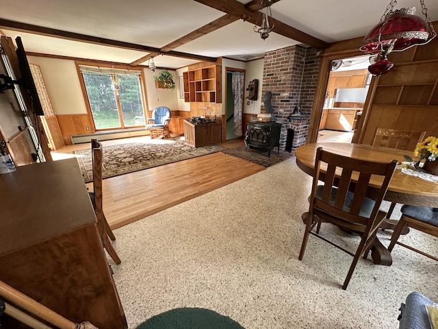 living room with a baseboard heating unit, beamed ceiling, wooden walls, hardwood / wood-style flooring, and a wood stove