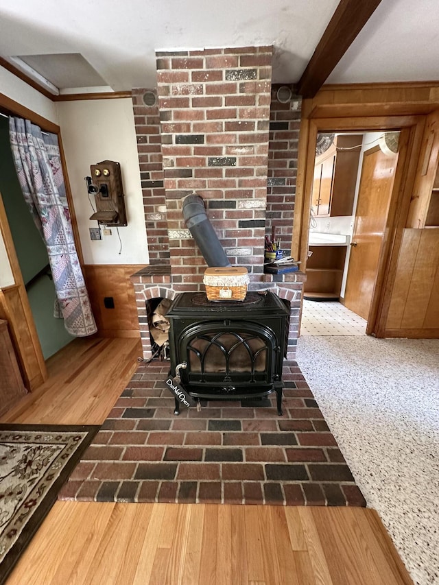 interior details with beamed ceiling, wooden walls, and a wood stove