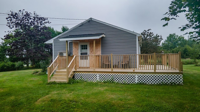 back of property with a wooden deck and a lawn