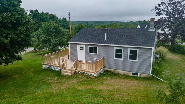 rear view of house with a wooden deck and a lawn