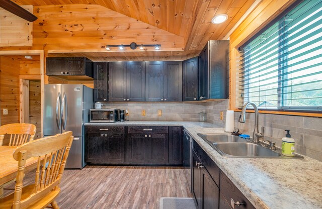 kitchen featuring lofted ceiling, sink, tasteful backsplash, appliances with stainless steel finishes, and light hardwood / wood-style floors