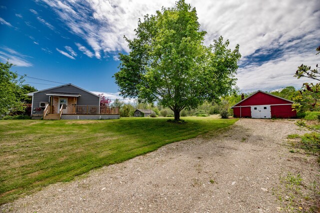 14 Porter St, Searsport, ME 04974 - view of green lawn featuring a deck, a detached garage, driveway, an outbuilding, and an outdoor structure