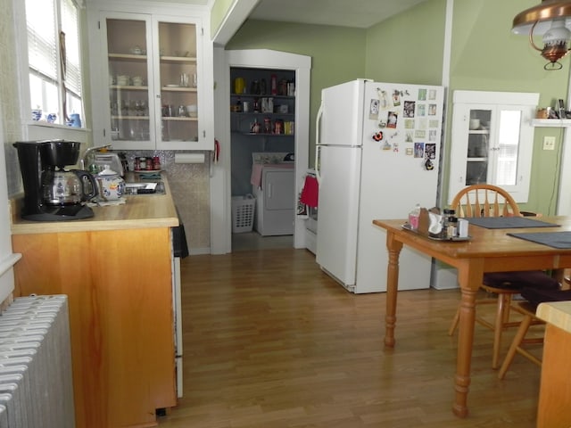 kitchen featuring washer / clothes dryer, white fridge, light hardwood / wood-style flooring, and radiator heating unit