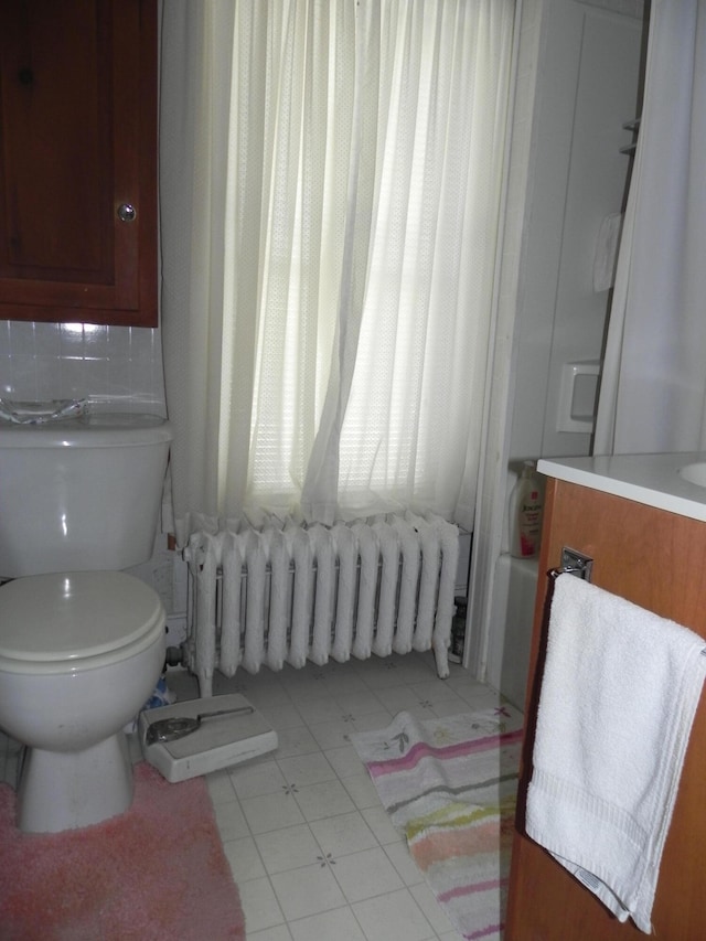 bathroom featuring tile floors, vanity, toilet, and radiator