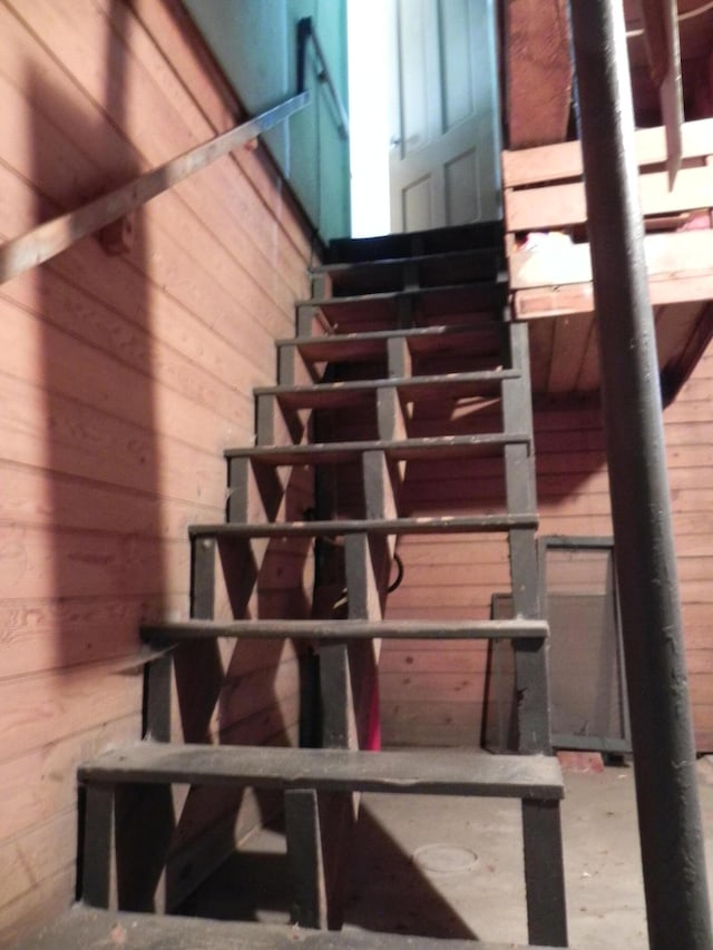 stairway featuring wood walls