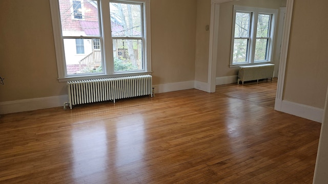 spare room with plenty of natural light, radiator heating unit, and hardwood / wood-style flooring