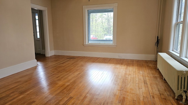 spare room with radiator heating unit and light wood-type flooring