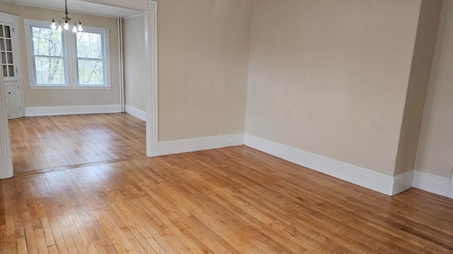 empty room with a notable chandelier and light wood-type flooring