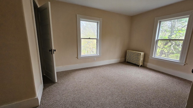 carpeted empty room featuring radiator heating unit