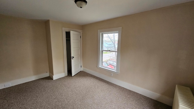 unfurnished bedroom featuring radiator heating unit, a closet, and carpet floors