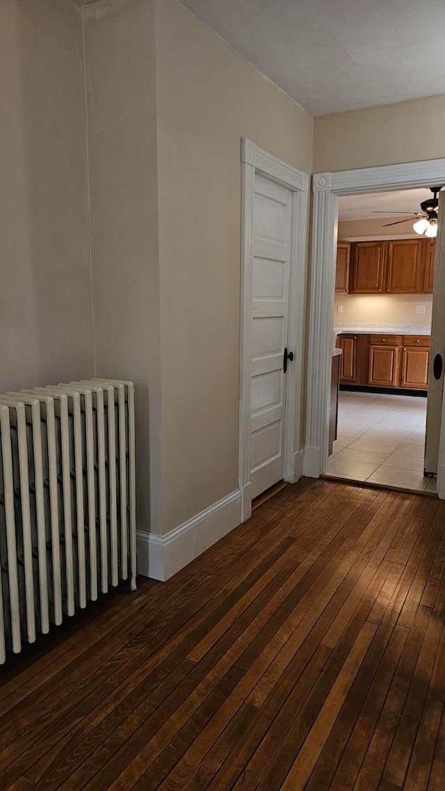 unfurnished room with ceiling fan, hardwood / wood-style flooring, and radiator