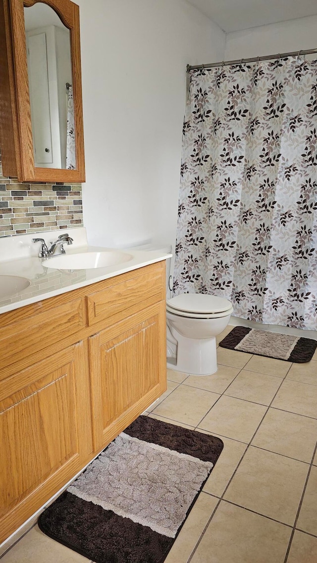 bathroom with tile patterned flooring, backsplash, walk in shower, toilet, and vanity