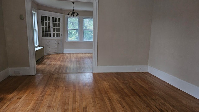 empty room with hardwood / wood-style floors and a chandelier