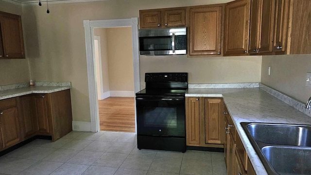 kitchen featuring crown molding, electric range, sink, and light tile patterned flooring