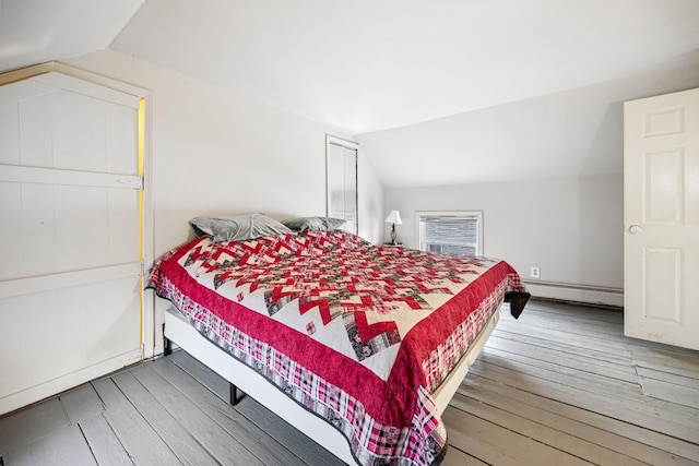 bedroom featuring hardwood / wood-style floors, a baseboard heating unit, and lofted ceiling