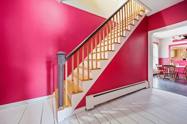 stairs featuring wood-type flooring and a baseboard radiator