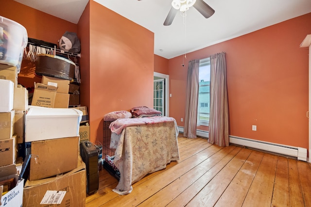 bedroom featuring a baseboard heating unit, wood-type flooring, and ceiling fan