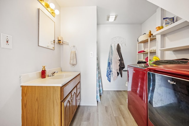 bathroom with washer and dryer, vanity with extensive cabinet space, and hardwood / wood-style flooring