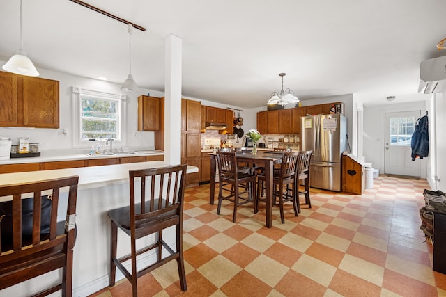 tiled dining room featuring sink, a wealth of natural light, an inviting chandelier, and a wall mounted air conditioner