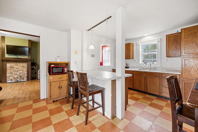 kitchen featuring black microwave, light tile floors, hanging light fixtures, sink, and a kitchen bar