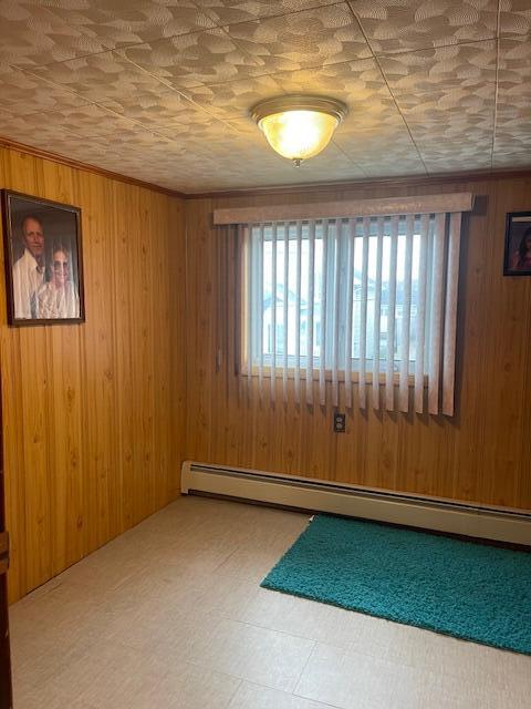 spare room with baseboard heating and wood walls