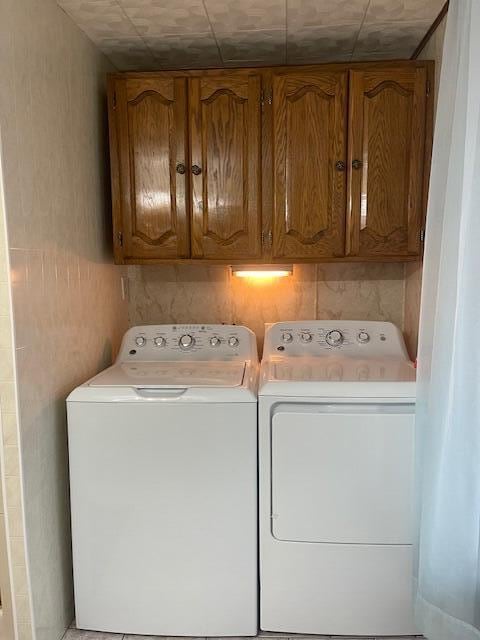 washroom with washing machine and clothes dryer and cabinets