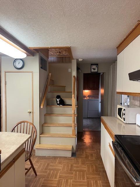 interior space featuring a textured ceiling, washer and clothes dryer, and parquet floors