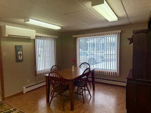 dining room featuring baseboard heating, a wall mounted AC, a wealth of natural light, and parquet floors