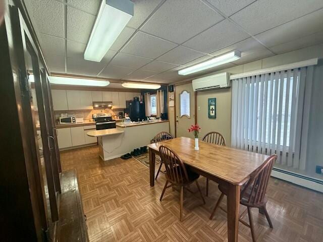 dining area with a wall mounted AC, light parquet floors, a baseboard radiator, and a drop ceiling