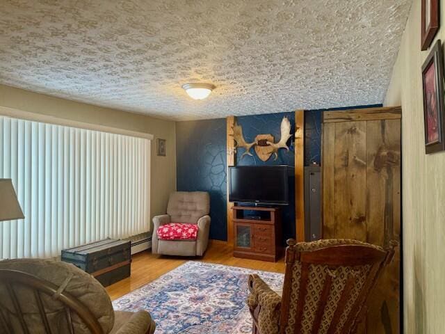 sitting room with a textured ceiling, baseboard heating, and light hardwood / wood-style floors