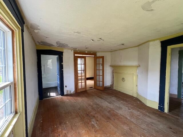 unfurnished living room featuring a wealth of natural light, french doors, and hardwood / wood-style flooring