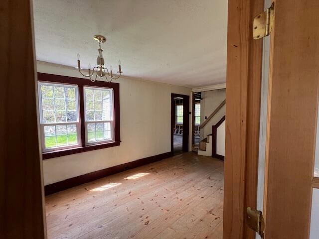 empty room featuring a notable chandelier and wood-type flooring