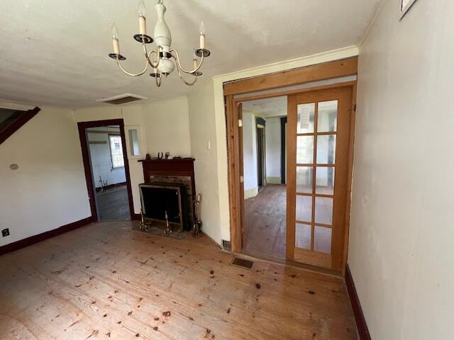 unfurnished living room with a notable chandelier, french doors, and wood-type flooring