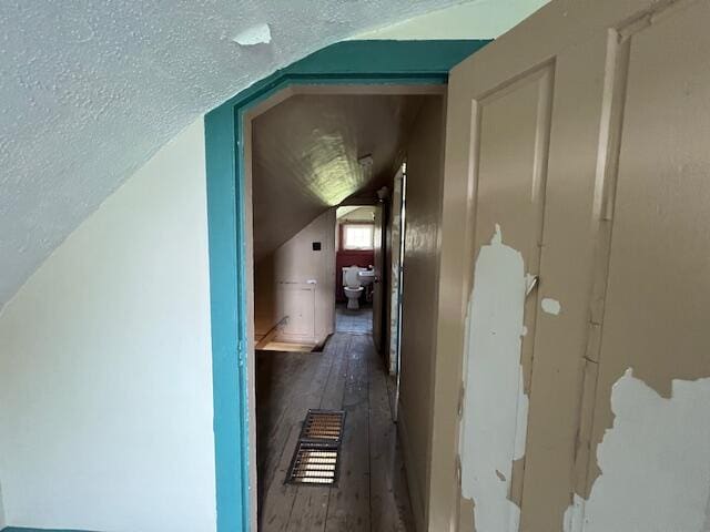 corridor with a textured ceiling, lofted ceiling, and dark wood-type flooring