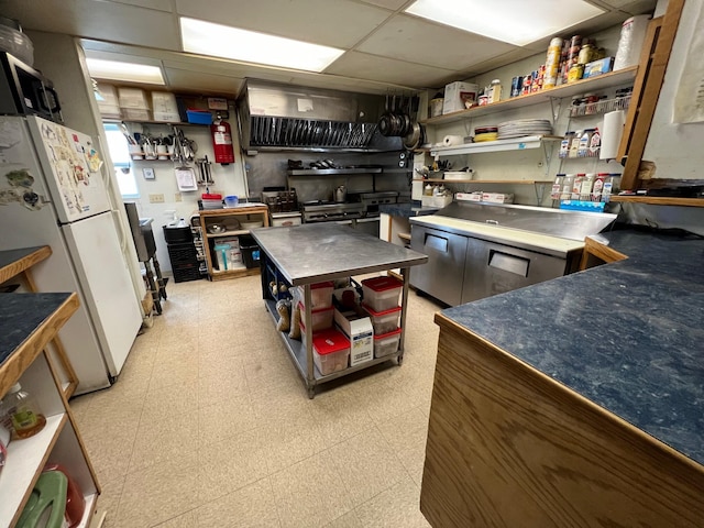 9 Tenney Hill Rd, Monson, ME 04464 - kitchen featuring white refrigerator, a drop ceiling, stainless steel counters, a center island, and light tile floors