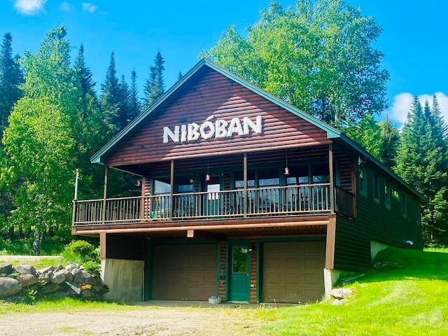 cabin with a garage, a front lawn, and a balcony