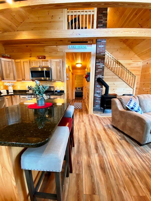 dining room with brick wall, wooden walls, a wood stove, and light hardwood / wood-style flooring