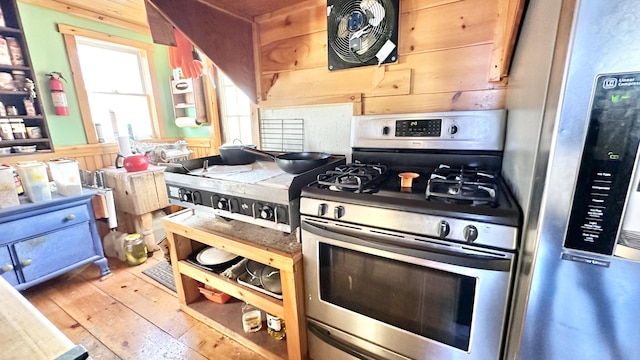 kitchen featuring wood-type flooring, stainless steel appliances, and wooden walls