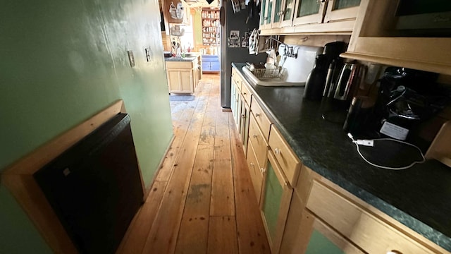 kitchen with black dishwasher, light brown cabinets, light wood-type flooring, and stainless steel fridge