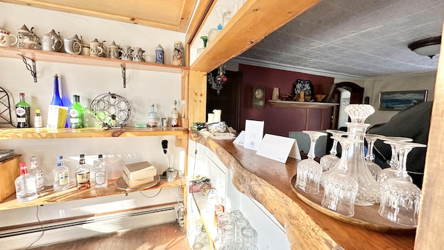 interior space with bar area, wood-type flooring, and a baseboard heating unit