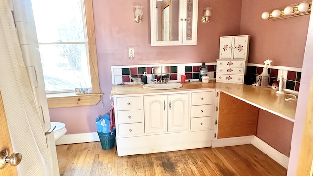 bathroom with tasteful backsplash, hardwood / wood-style floors, vanity, and toilet