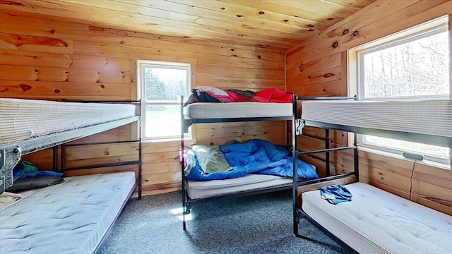 carpeted bedroom with wooden walls and wood ceiling