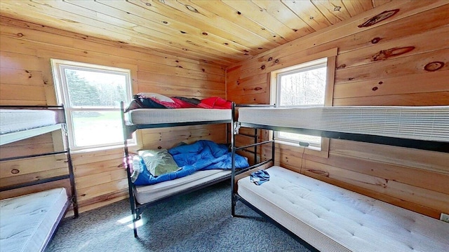 bedroom with wooden ceiling, carpet flooring, and wood walls