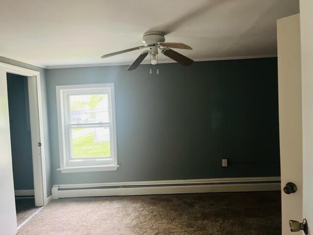 carpeted spare room with a baseboard heating unit and ceiling fan