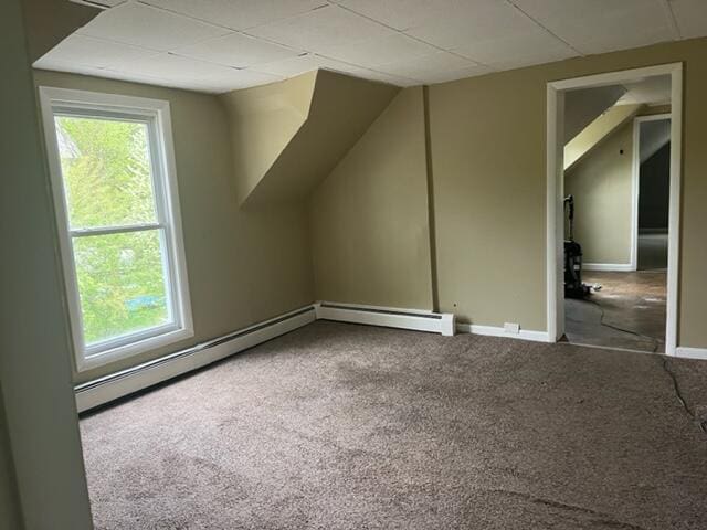 additional living space featuring a wealth of natural light, a baseboard heating unit, and carpet floors