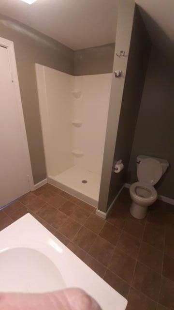 bathroom with tile flooring, a shower, and toilet