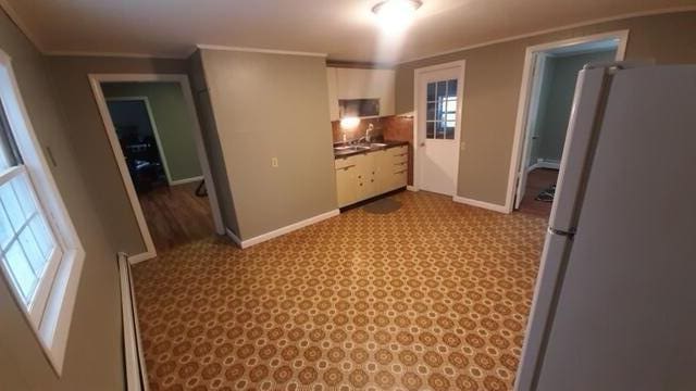 kitchen with white cabinetry, a healthy amount of sunlight, stainless steel refrigerator, and light tile floors